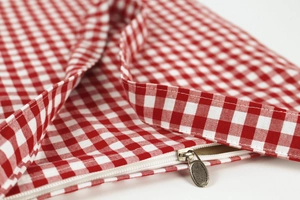 Detail of red and white gingham tote bag featuring a smooth resin zipper and metal slider