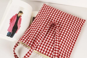 Close-up of red and white gingham fabric bag showing soft canvas texture and zipper detail