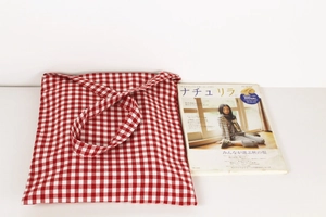 Detail of red gingham canvas tote bag with cotton-linen texture next to a magazine