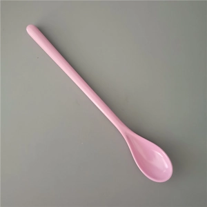 Close-up of pink long-handled plastic melamine dessert spoon on neutral gray background
