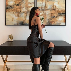 Détail d'une élégante robe noire en soie à col bénitier avec dos nu et fente latérale