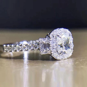 Macro shot of silver wedding ring with cushion-cut center stone and pave zircon details