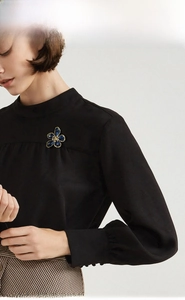 Blue crystal flower brooch pin with golden petals shown on a black shirt collar