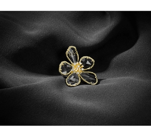 Detail of vintage flower brooch with dark grey crystal petals and gold-plated edges