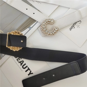 Detail showing elastic black belt and white faux leather belt with rhinestone buckles