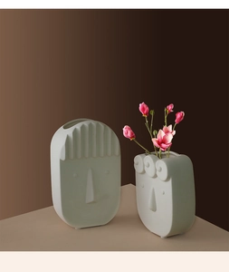 Close-up of matte white ceramic vases with creative abstract face designs and textures