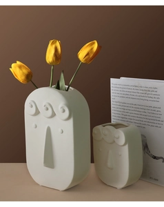 Detailed macro view of two matte white ceramic face vases with Nordic artistic textures