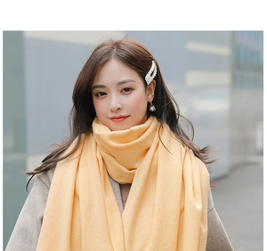 Detail of soft pale yellow cashmere scarf with fringes shown on a model in street style