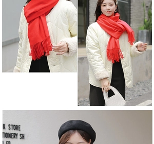Detailed view of red cashmere scarf with fringe tassels worn in a lifestyle outdoor setting