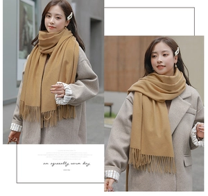 Detailed view of the camel cashmere scarf with elegant fringe texture on a city street