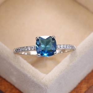 Elegant square blue zircon ring in silver with micro-paved crystals on velvet background
