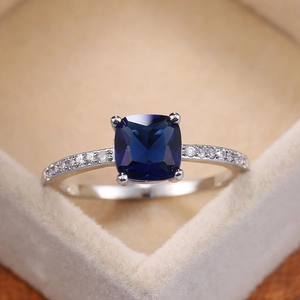 Macro detail of cushion-cut blue sapphire ring with pavé zircon band in a jewelry box