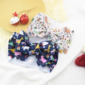 Detail view of two Christmas themed baby headbands with festive patterns and large bows