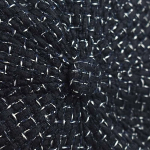Macro shot of black tweed newsboy hat fabric showing texture and top button detail