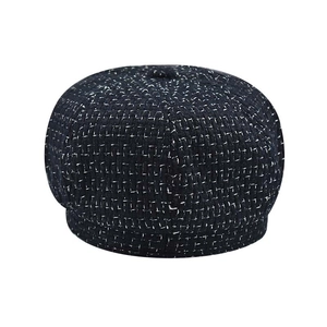 Detailed view of the black and white tweed fabric and top button on a classic beret