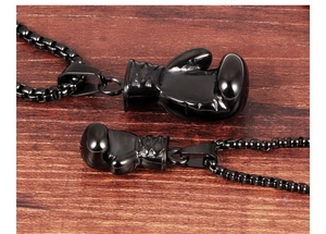 Detail of black stainless steel boxing glove pendants on box chain with wood background