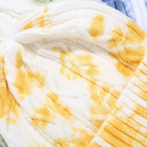 Close-up of the yellow and white tie-dye knit beanie showing detailed cable knit texture