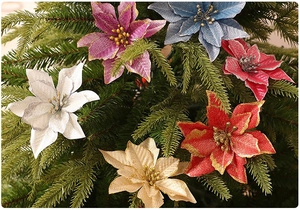 Close-up of colorful glitter poinsettia flowers on green Christmas tree branches