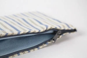 Macro view of blue striped cotton fabric texture and grey metal zipper of the storage bag