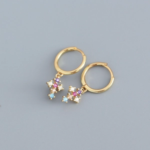Detail of gold huggie earrings with colorful zircon cross charms on gray background