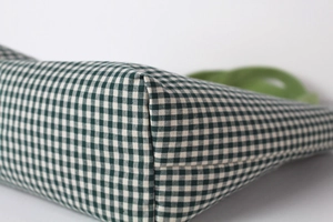 Detail shot of sturdy reinforced stitching on the base of a green gingham canvas bag