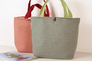 Detail of plaid canvas tote bags showing textured fabric and vintage metal buckle