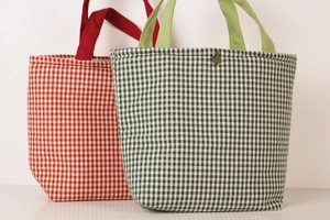 Close-up of red and green plaid canvas lunch bags with sturdy handles and metal buckle