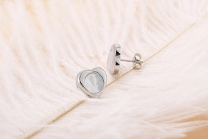 Detail of heart shell earrings in silver stainless steel on soft pink feather backdrop