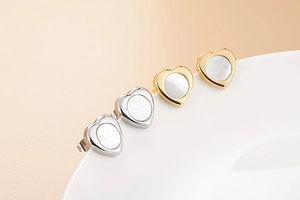 Macro shot of heart-shaped earrings in gold and silver with white shell inlay detail