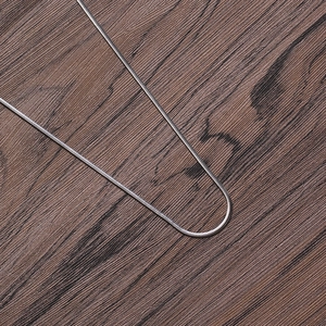 Detailed view of 2mm silver stainless steel snake chain on a rustic wooden background