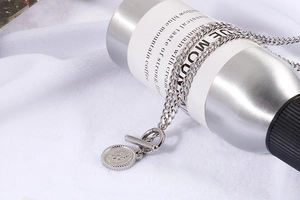 Macro detail of silver coin necklace with Elizabeth II relief and OT toggle clasp