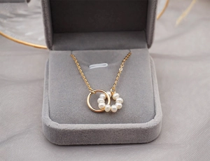 Detail of interlocking gold hoop and pearl pendant on a thin chain in a gift box