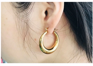Detail showing 18K gold crescent hoop earrings on ear for stylish fashion look