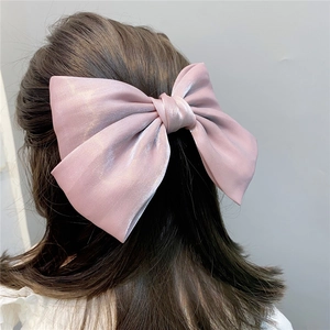 Detailed back view of a large pink pearlescent satin bow hair clip for women