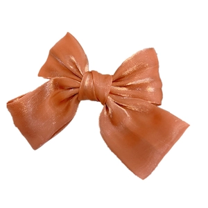 Detail einer großen orangen Organza-Schleife-Haarspange mit schimmerndem Stoff