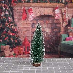 Close-up of mini artificial Christmas tree with snow-flocked needles on round wooden base