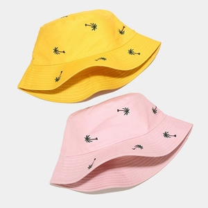 Close-up of yellow and pink bucket hats featuring detailed coconut tree embroidery