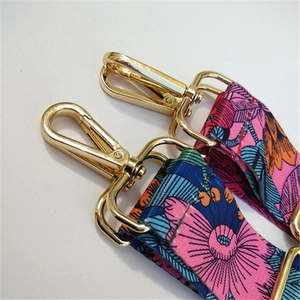 Close-up of floral fabric bag straps with golden metal hooks and adjustable buckles