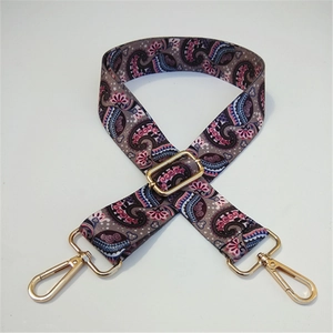 Detailed view of paisley pattern strap with golden metal swivel hooks and adjuster