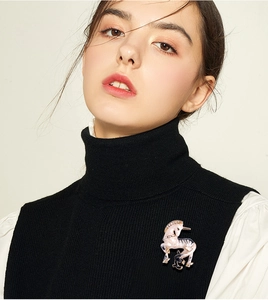 Detailed view of an elegant unicorn brooch with pink rhinestones on a black knit top