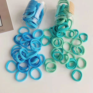 Close-up of blue and green seamless elastic hair ties spilling out of clear jars