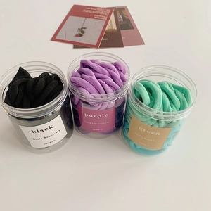 Detail of high-elastic seamless hair ties in transparent jars, black purple green colors