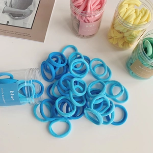 Close-up of pastel seamless hair ties in a plastic jar with rainbow gradient colors