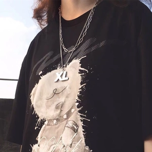 Double-layered stainless steel necklace with large XL letter pendant on black t-shirt