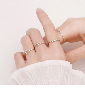Set of four silver constellation rings with cubic zirconia stones worn on a hand