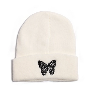 Close-up of butterfly embroidery on a cream-white knitted beanie with folded cuff