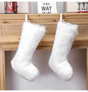 Close-up of two white plush Christmas stockings hanging on a wooden fireplace mantle