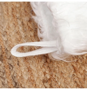 Close-up of plush white Christmas stocking with hanging loop on jute background