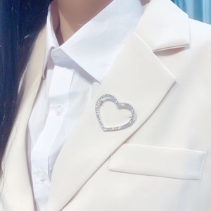 Close-up of sparkling heart-shaped brooch with silver setting on a white suit lapel