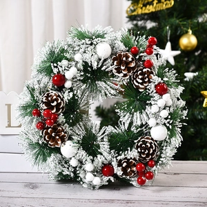Detail of Christmas wreath with snowy pine needles, red berries, and natural pine cones